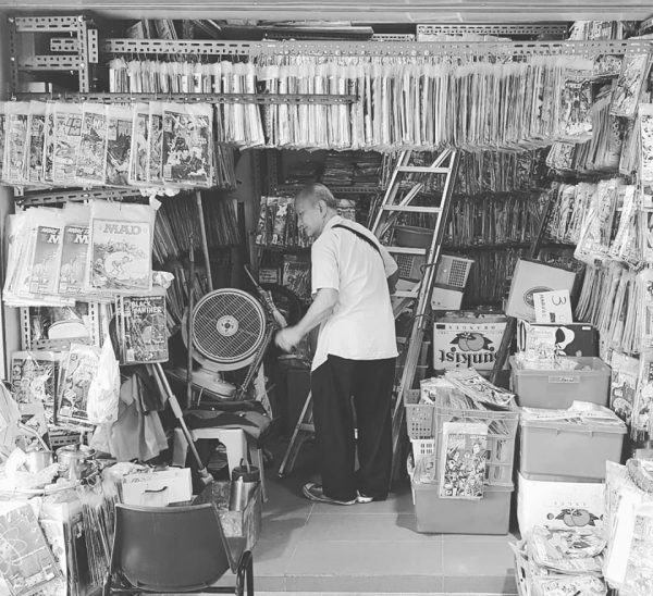 Mr. Low working inside his modest comic book shop, Silver Kris